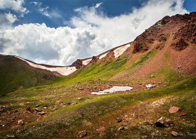 Banks of snow cling to the edges of the red mountain ridge